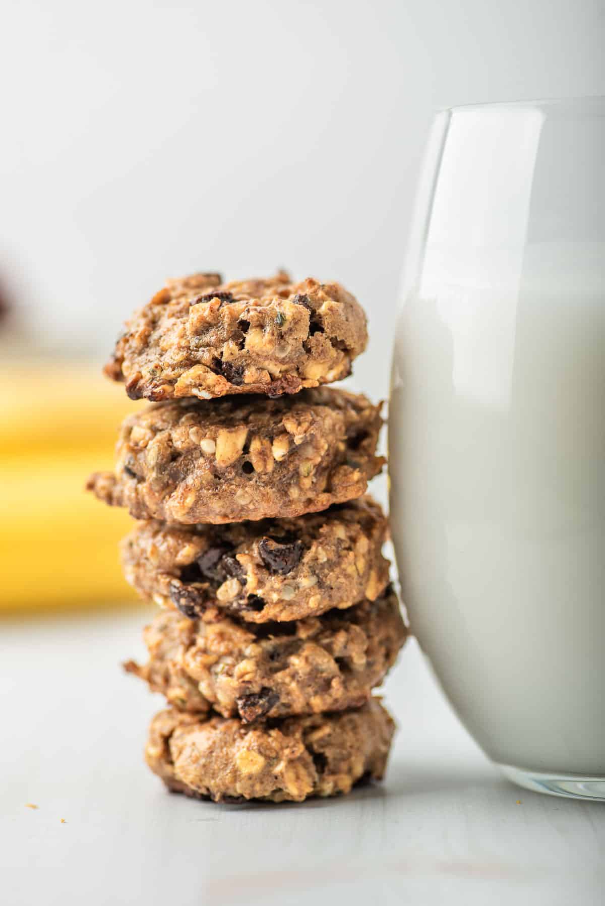 Cookies stacked next to a large glass of milk.