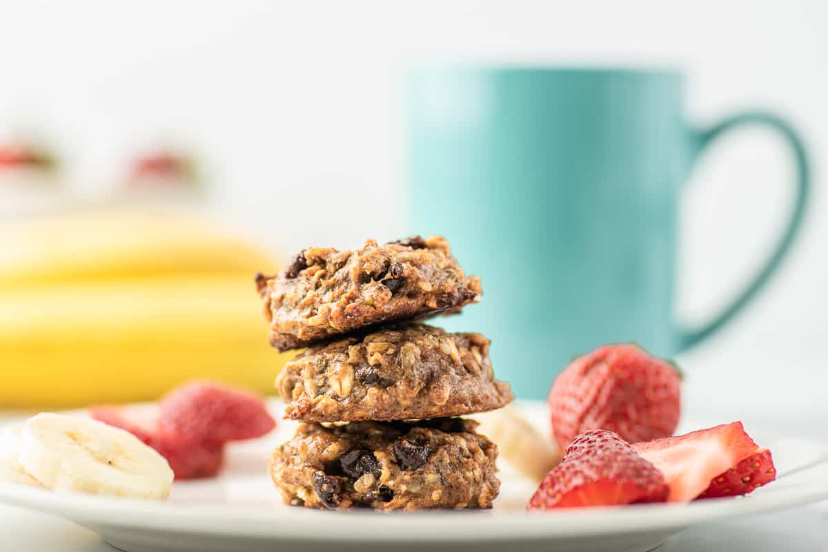 3 breakfast cookies on a plate with fruit.