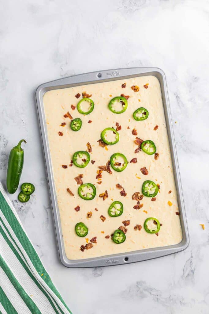 Uncooked sheet pan pancake with jalapeno and bacon.