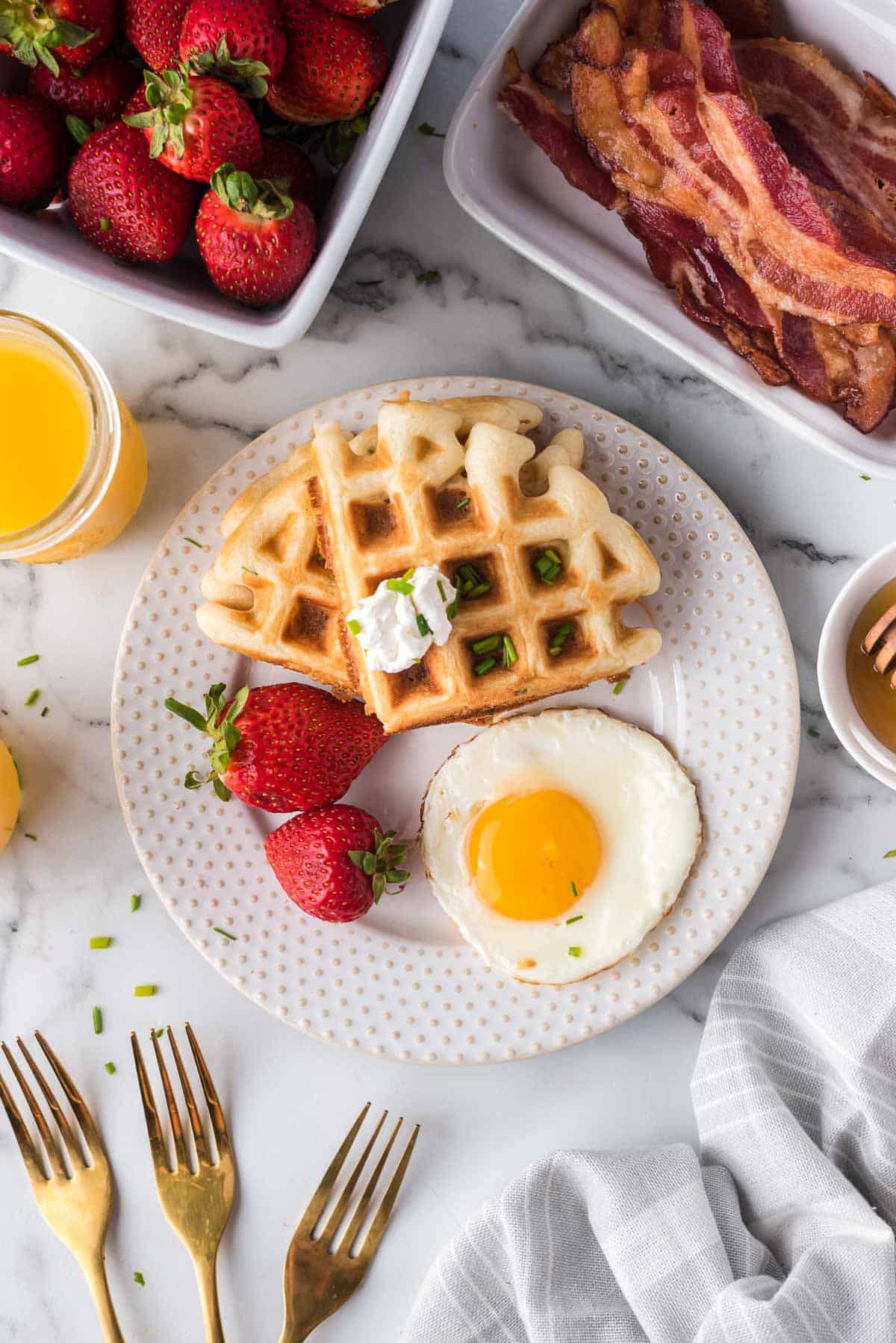 Overhead view of a plate with waffles, strawberries, and an egg.