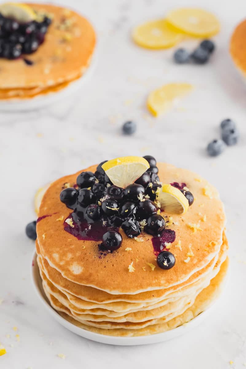 Stack of pancakes topped with lemons and blueberry sauce.