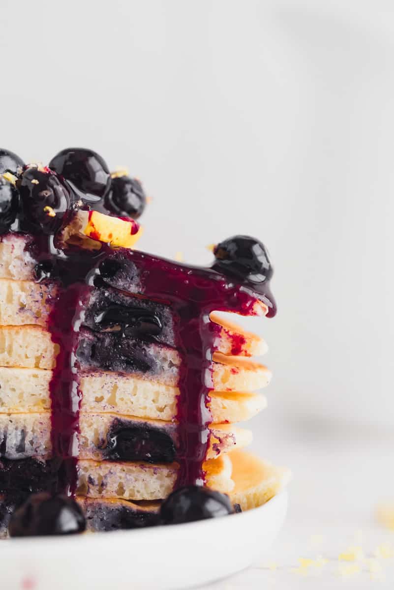 Close up of a stack of lemon blueberry pancakes with blueberry sauce.