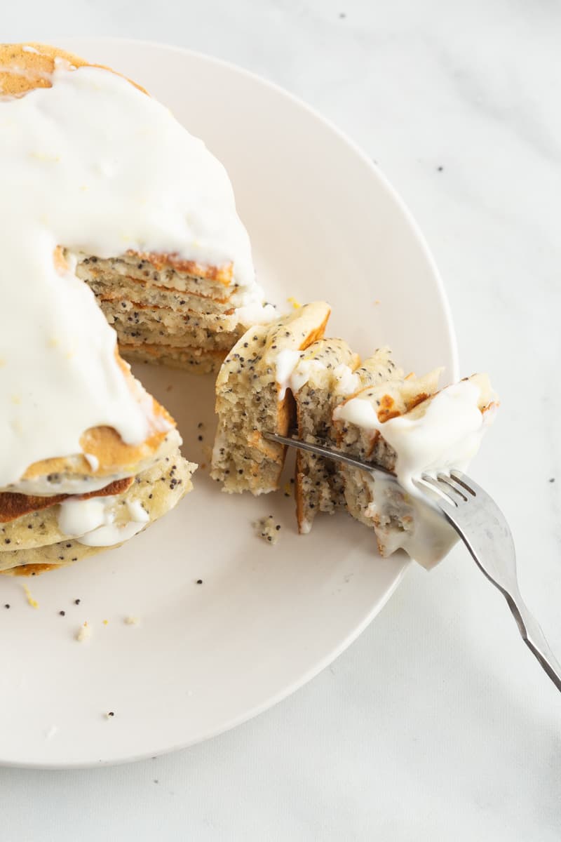 Stack of lemon pancakes with poppy seeds, a wedge cut out to show texture.