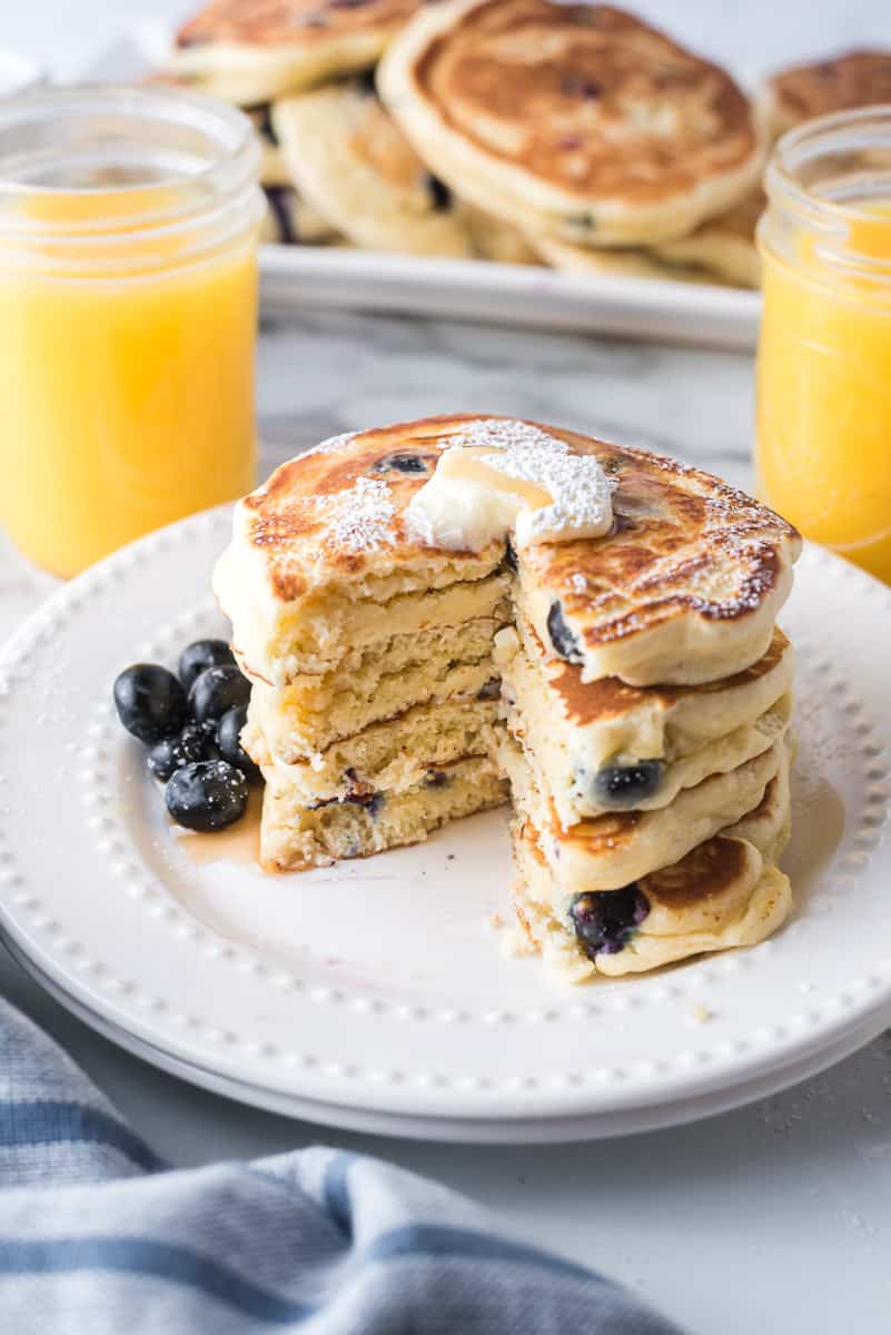 Stack of pancakes with slice cut out to show texture and blueberries inside.