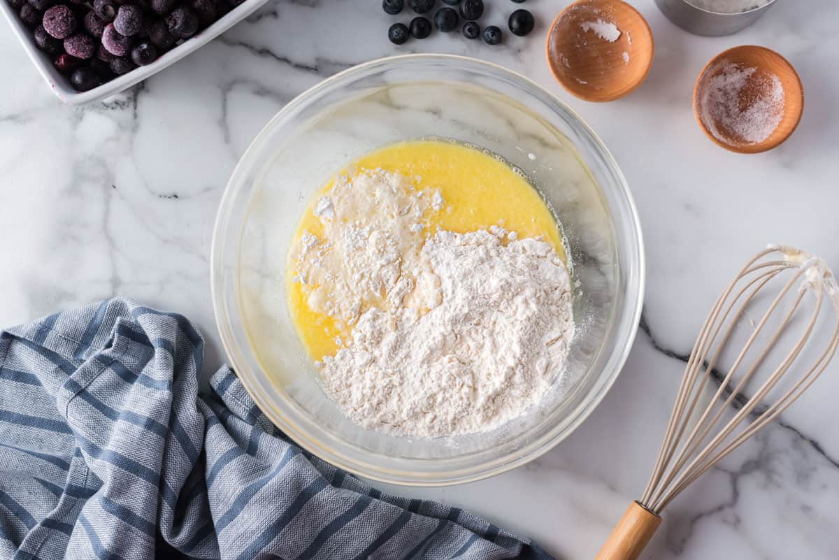 Dry ingredients for pancakes on top of wet ingredients. Whisk also pictured.