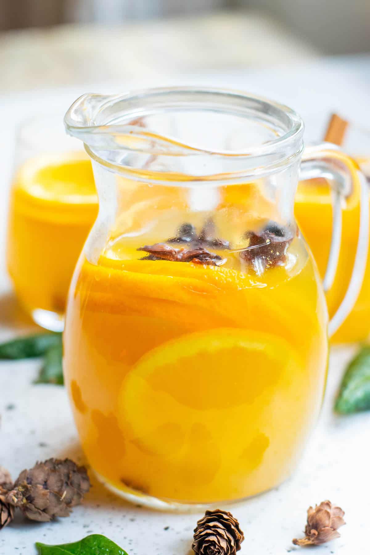 Pitcher of orange punch garnished with whole spices.