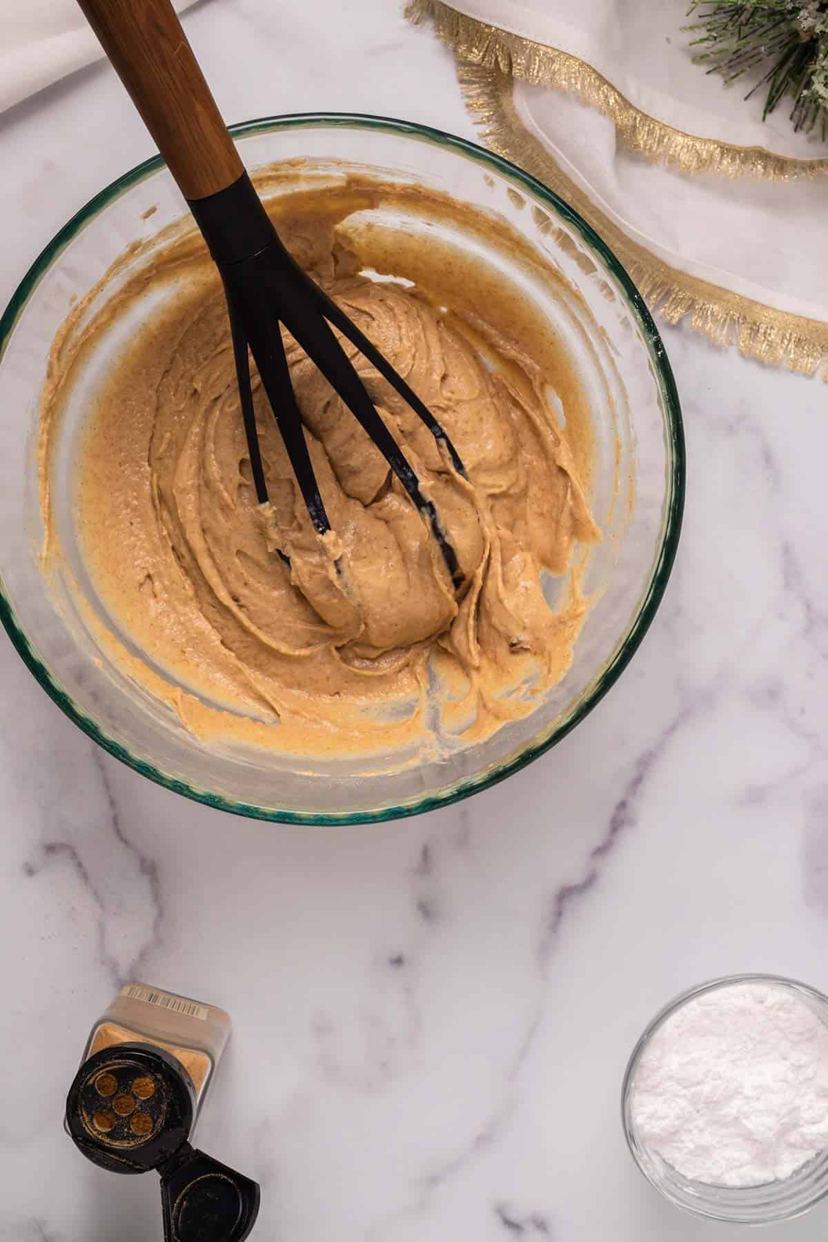 Donut batter in a bowl with a whisk.