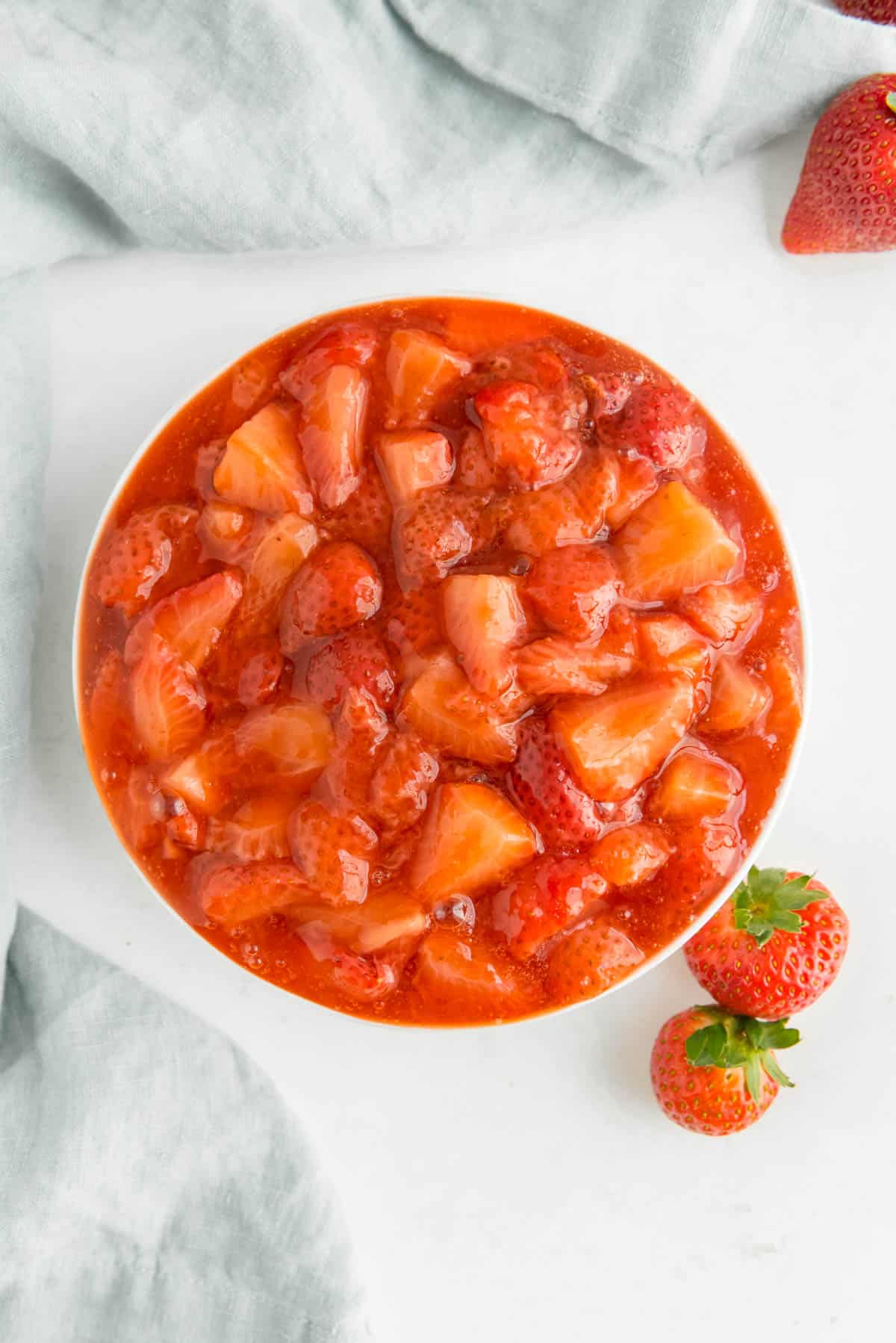 Overhead view of a large white bowl filled with strawberry sauce.