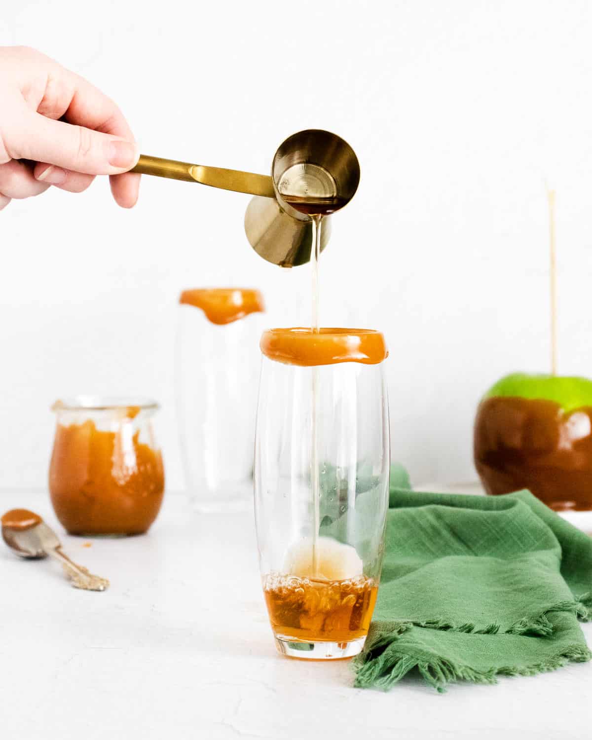 Apple cider being poured into a caramel-rimmed champagne flute.