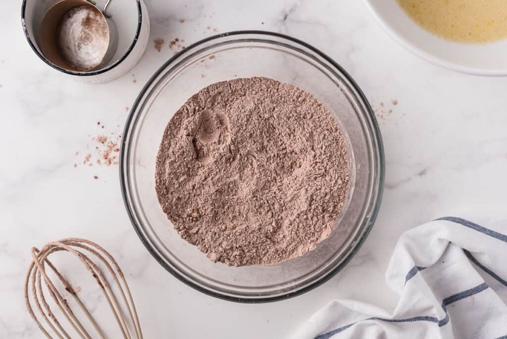 Dry ingredients with cocoa powder in a glass bowl.