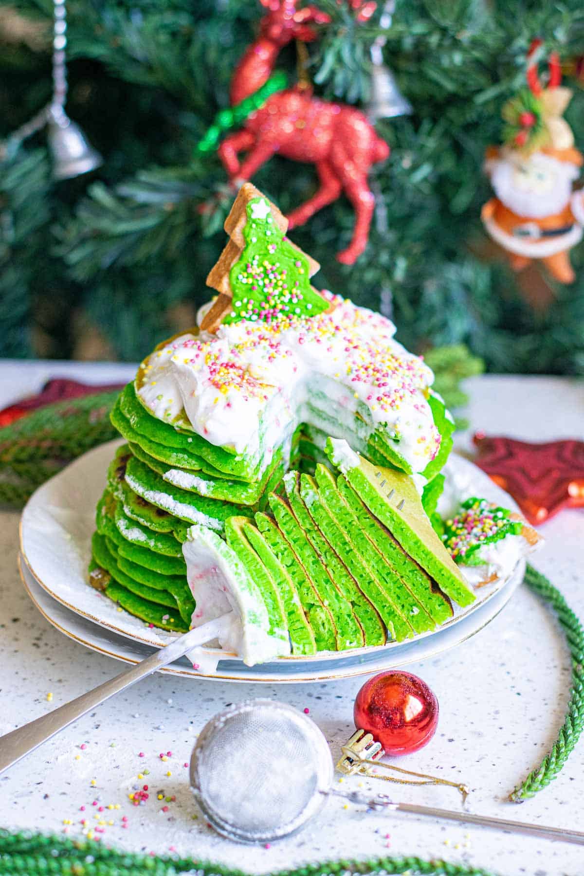 A wedge of green pancakes on a fork with the whole stack behind them.