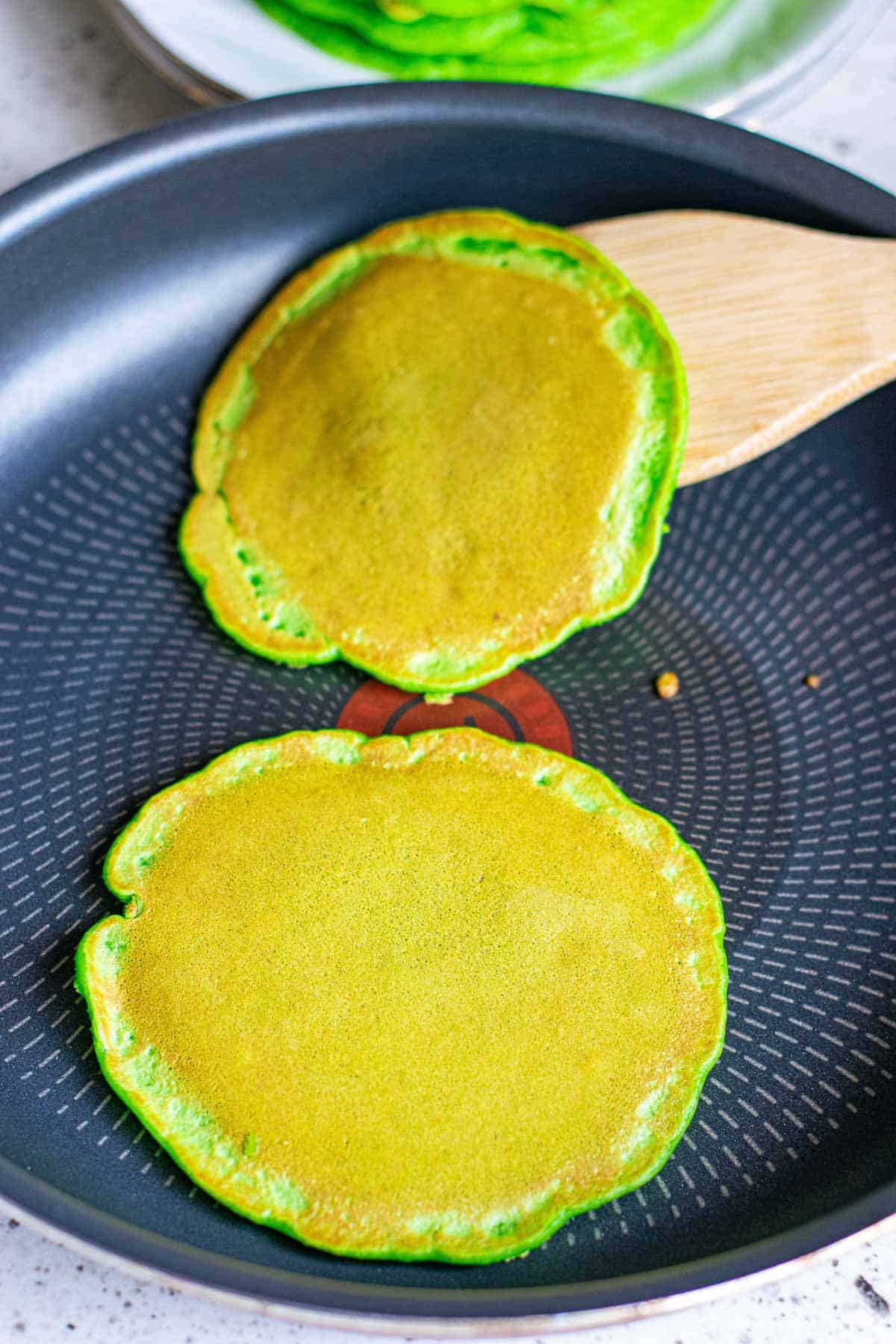 Green pancakes on a griddle.
