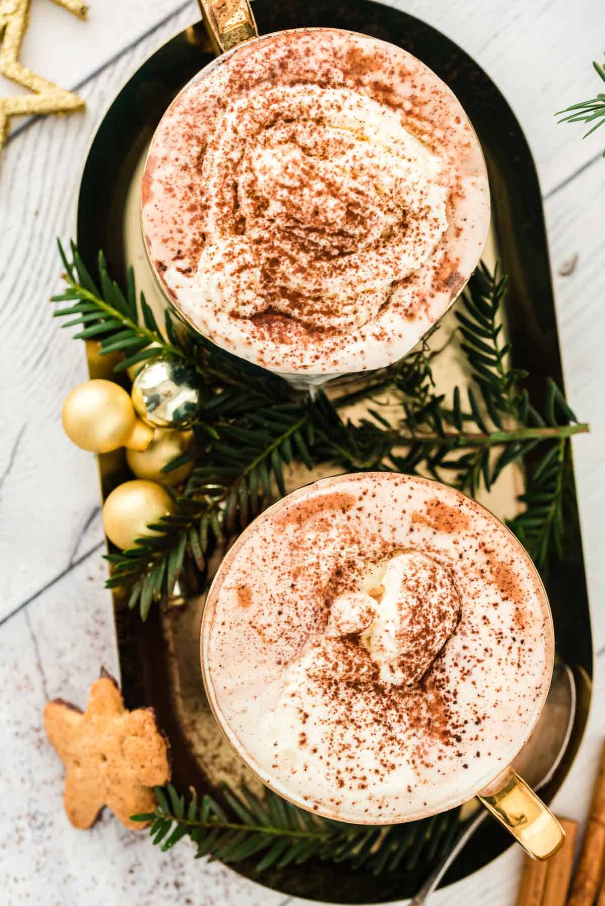 Two mugs of hot chocolate on a decorative tray.