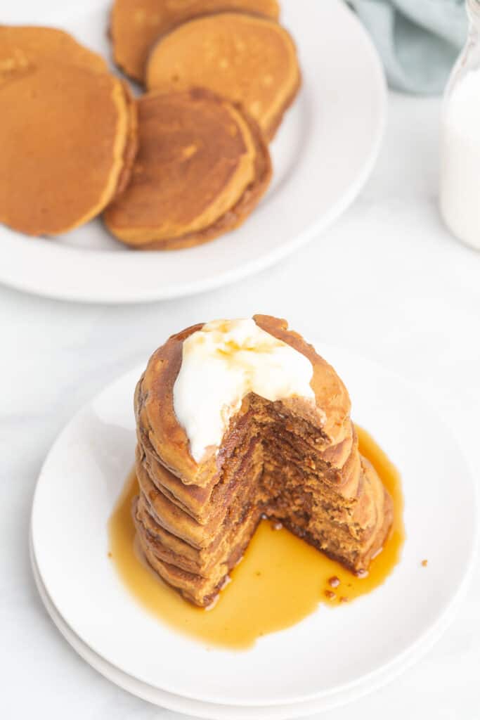 Pancakes topped with syrup and whipped cream.