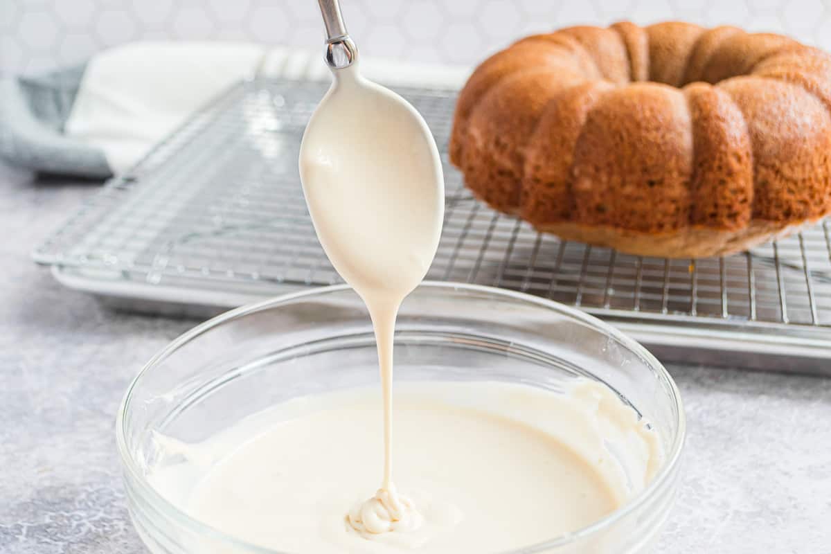 Cream cheese glaze being drizzled off spoon.