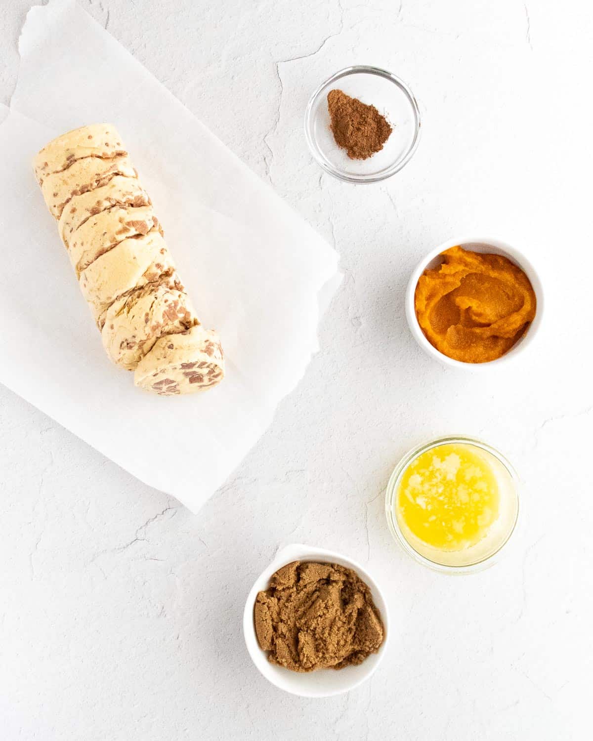 Overhead view of ingredients needed for pumpkin spice monkey bread muffins, on a white background.