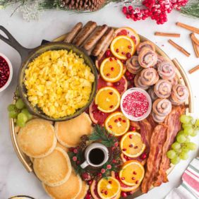 Assorted Christmas brunch items on a large wooden board with festive decorations nearby.