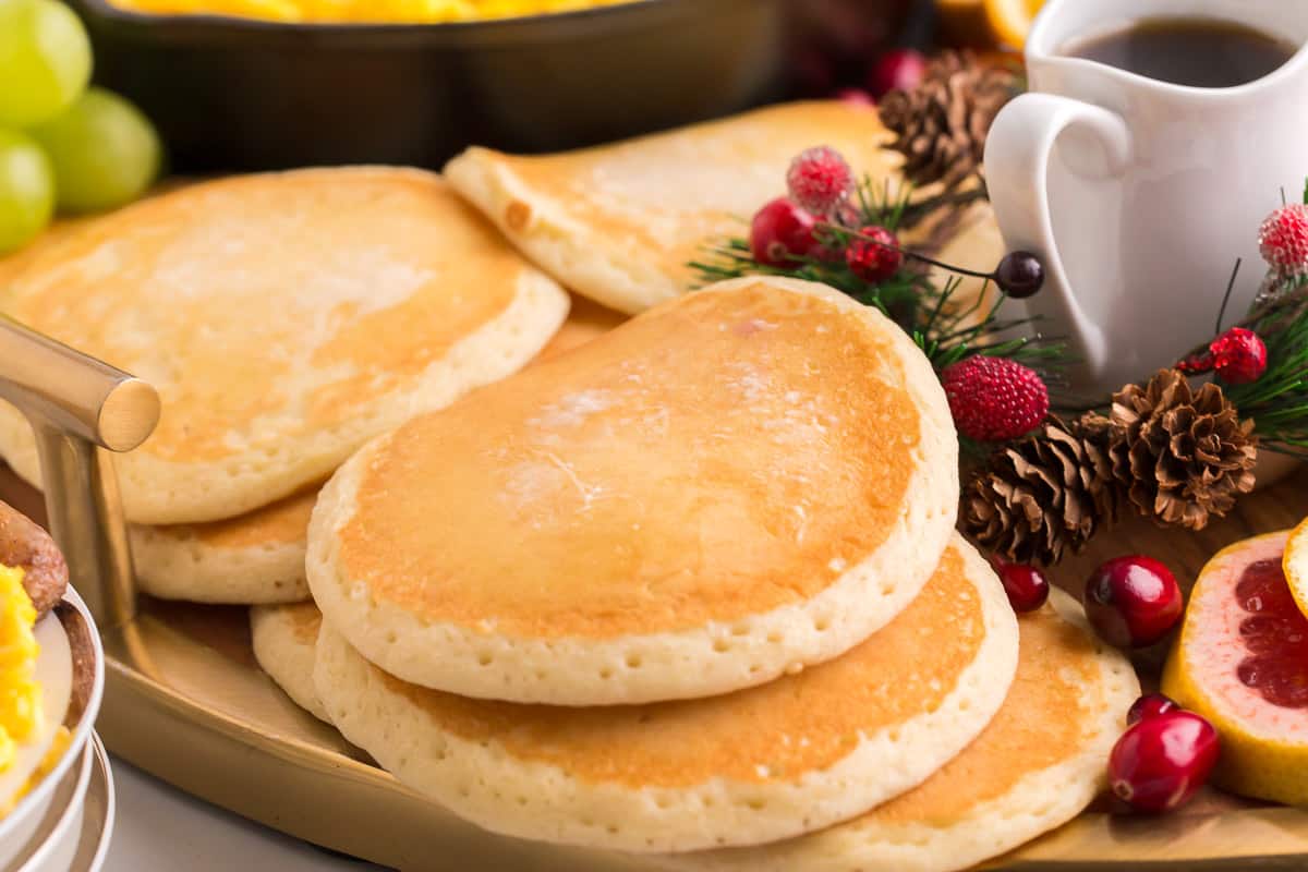 Cooked pancakes on a large platter with other breakfast items.