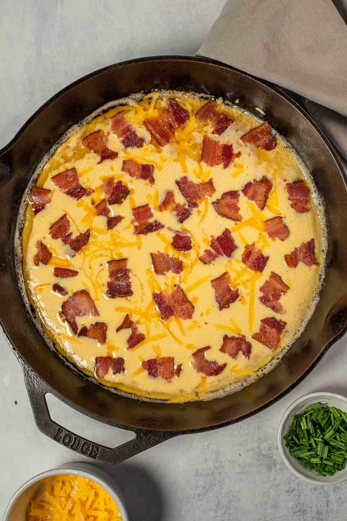 Uncooked dutch baby with bacon and cheeese.