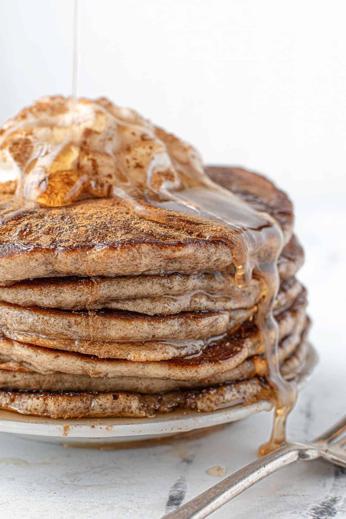 Stack of light brown pancakes with syrup dripping down the side.