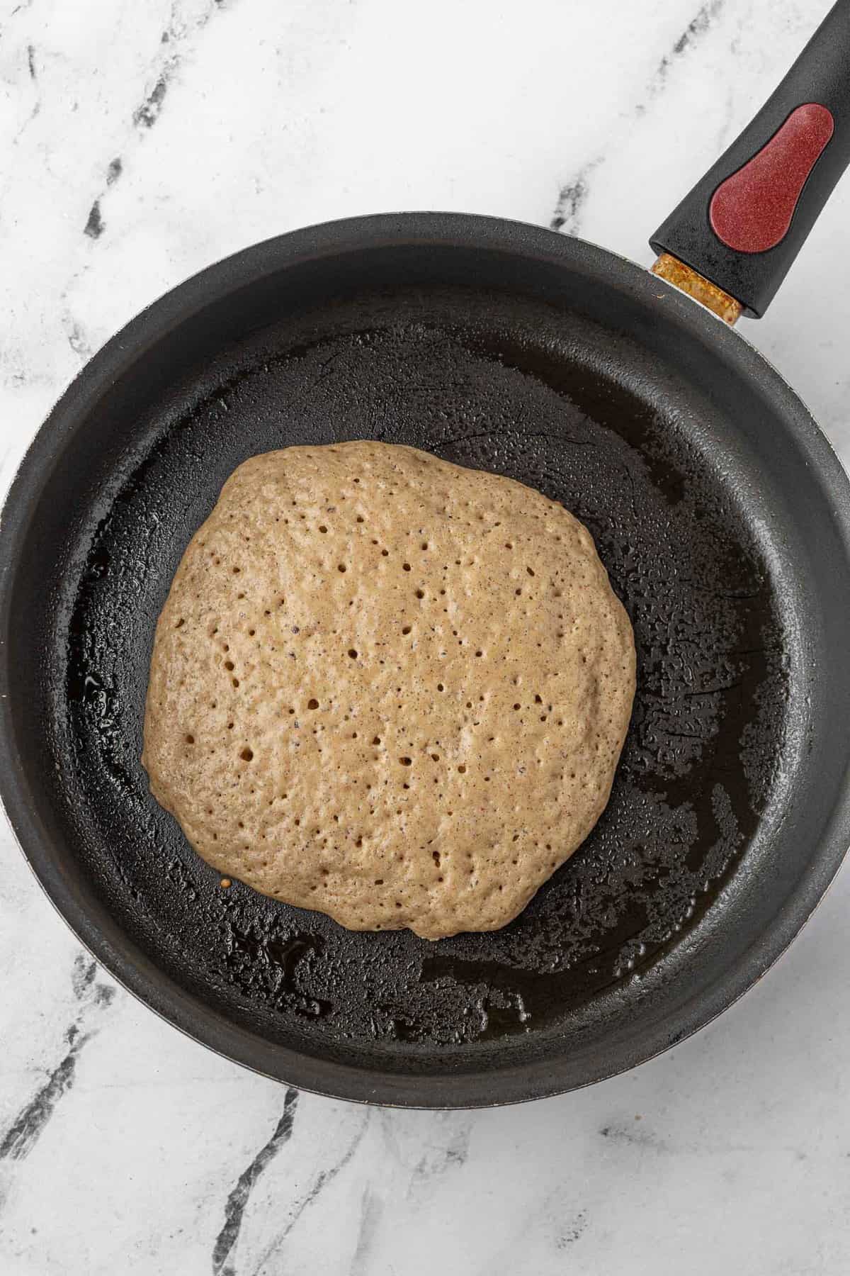 Pancake in a skillet, half cooked.