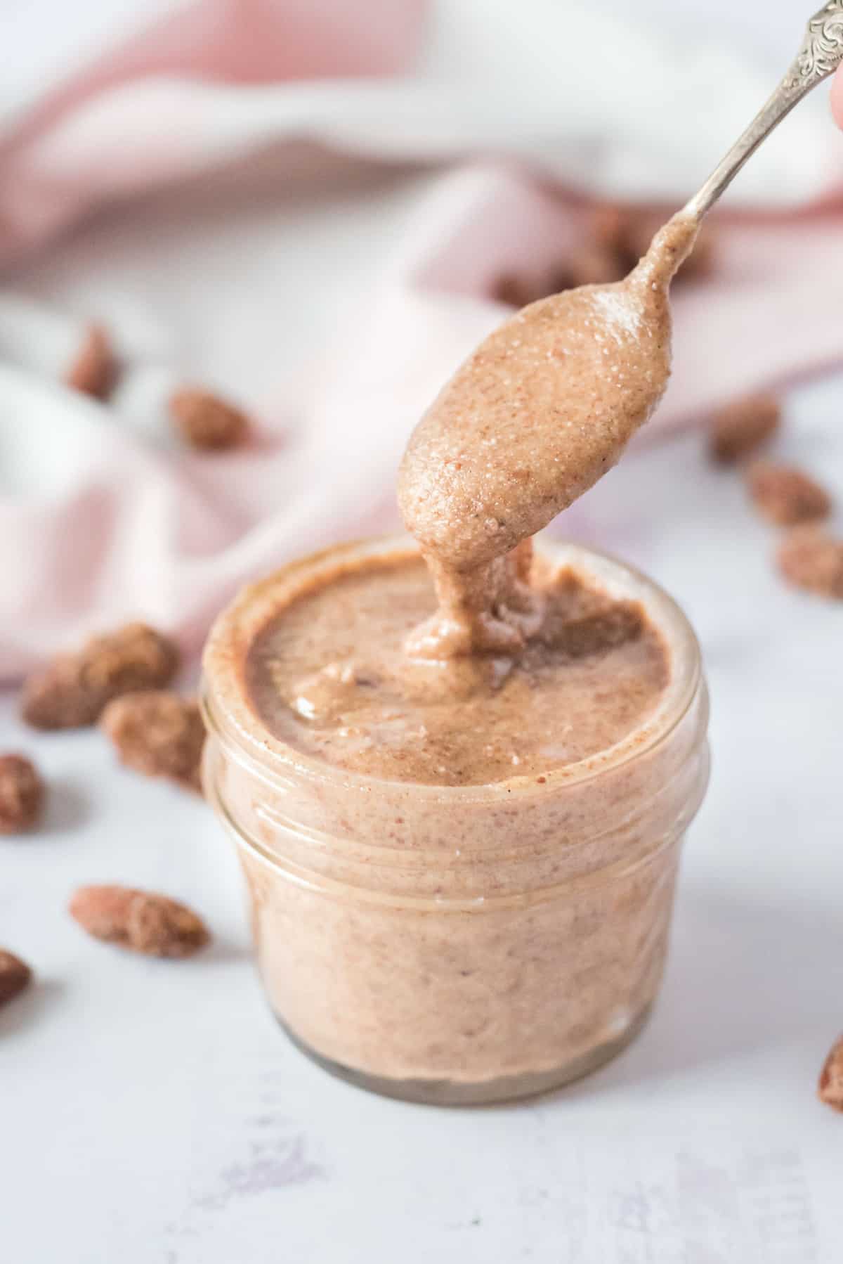 A spoon getting nut butter out of a jar.