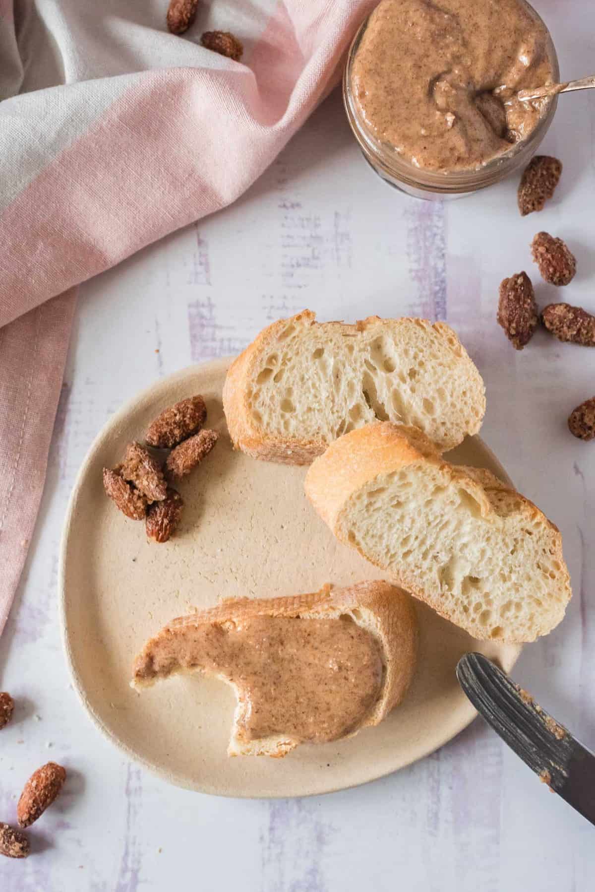 Almond butter spread on bread with more bread and a jar of almond butter nearby.