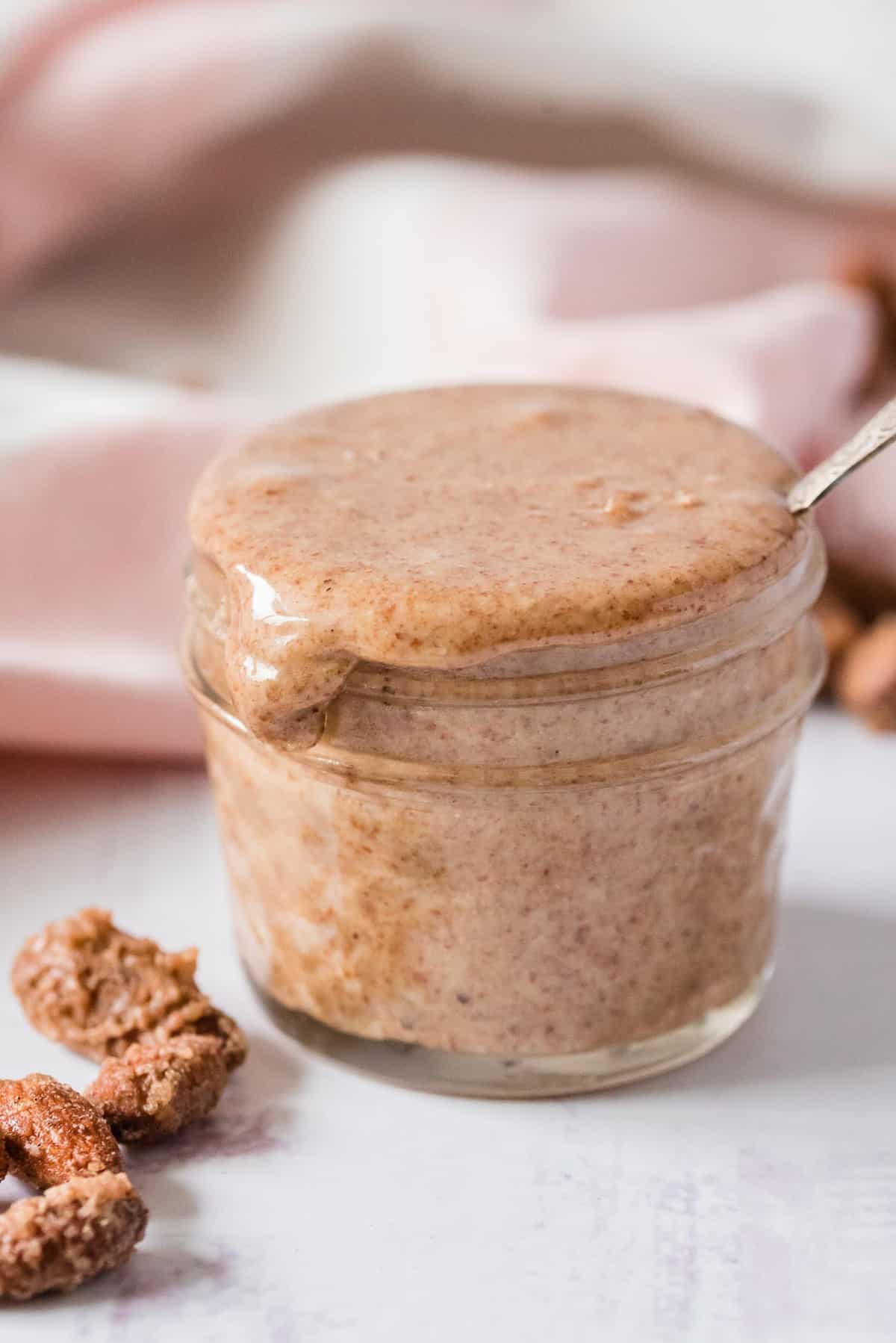 Almond butter overflowing from a small glass jar.