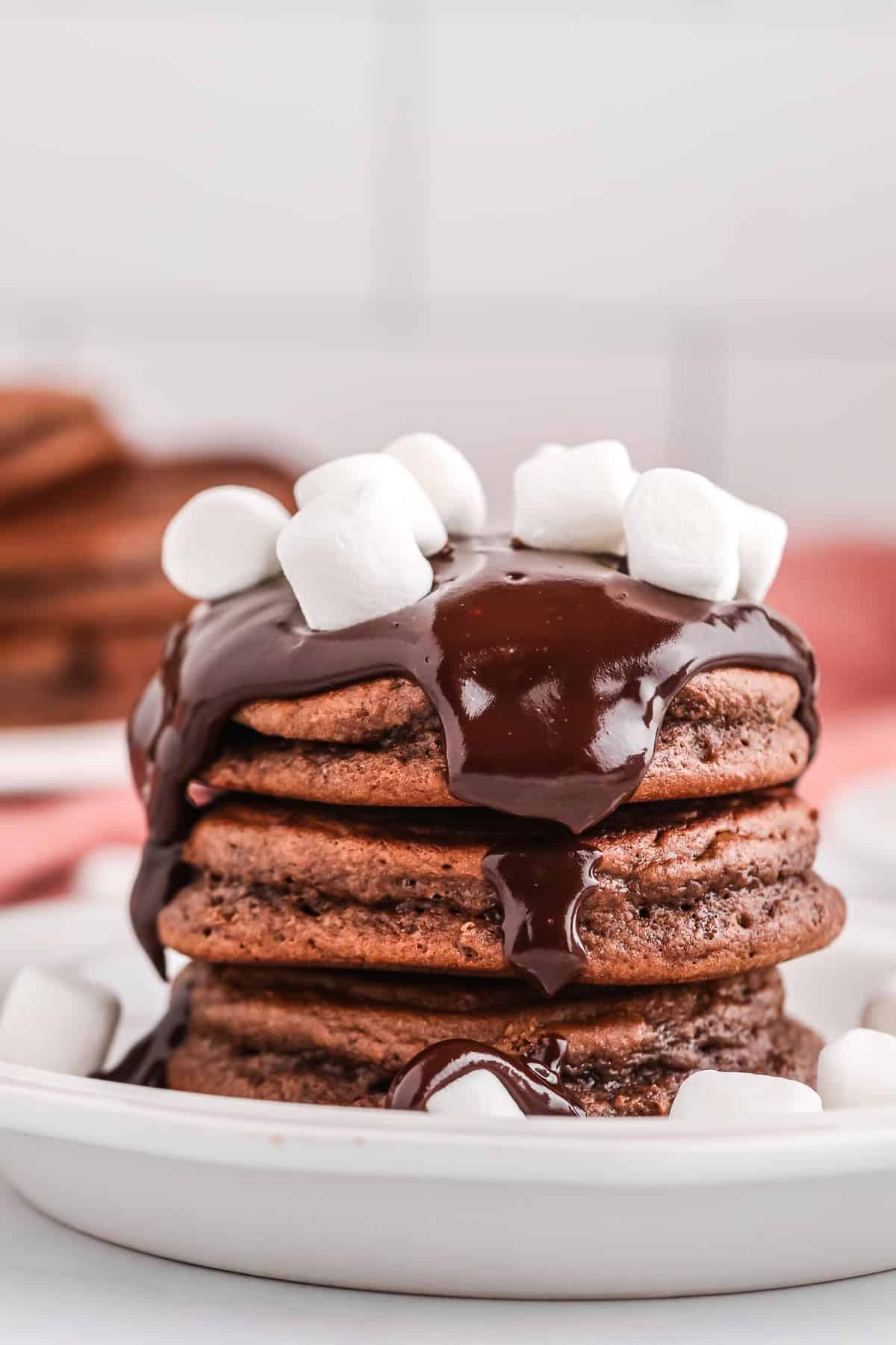 Stack of chocolate pancakes with chocolate ganache and marshmallows.