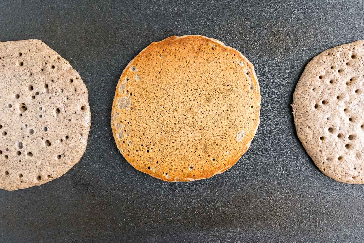 Pancakes on a black griddle.