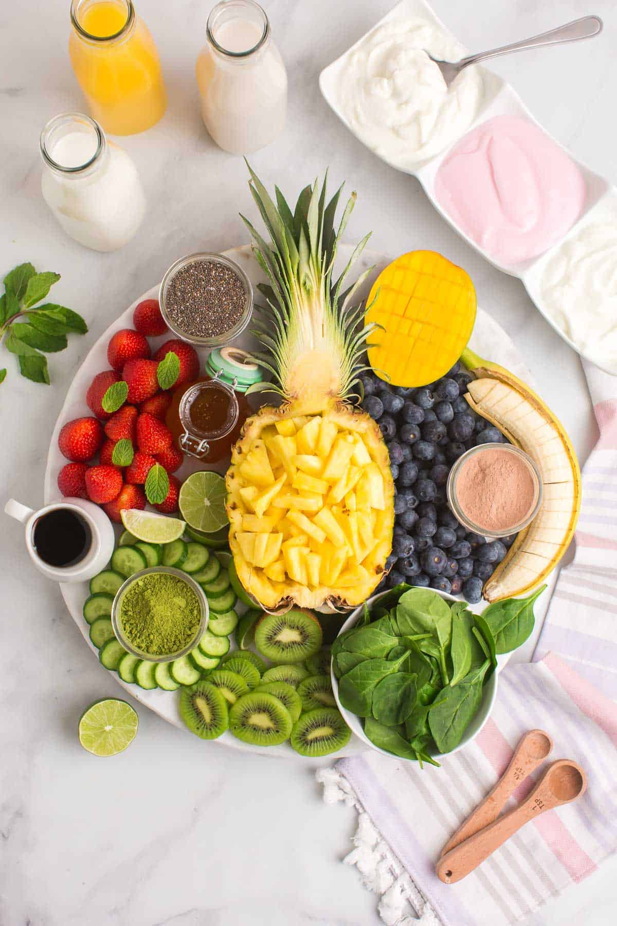 Fruit and assorted toppings arranged on a board for a smoothie bar.