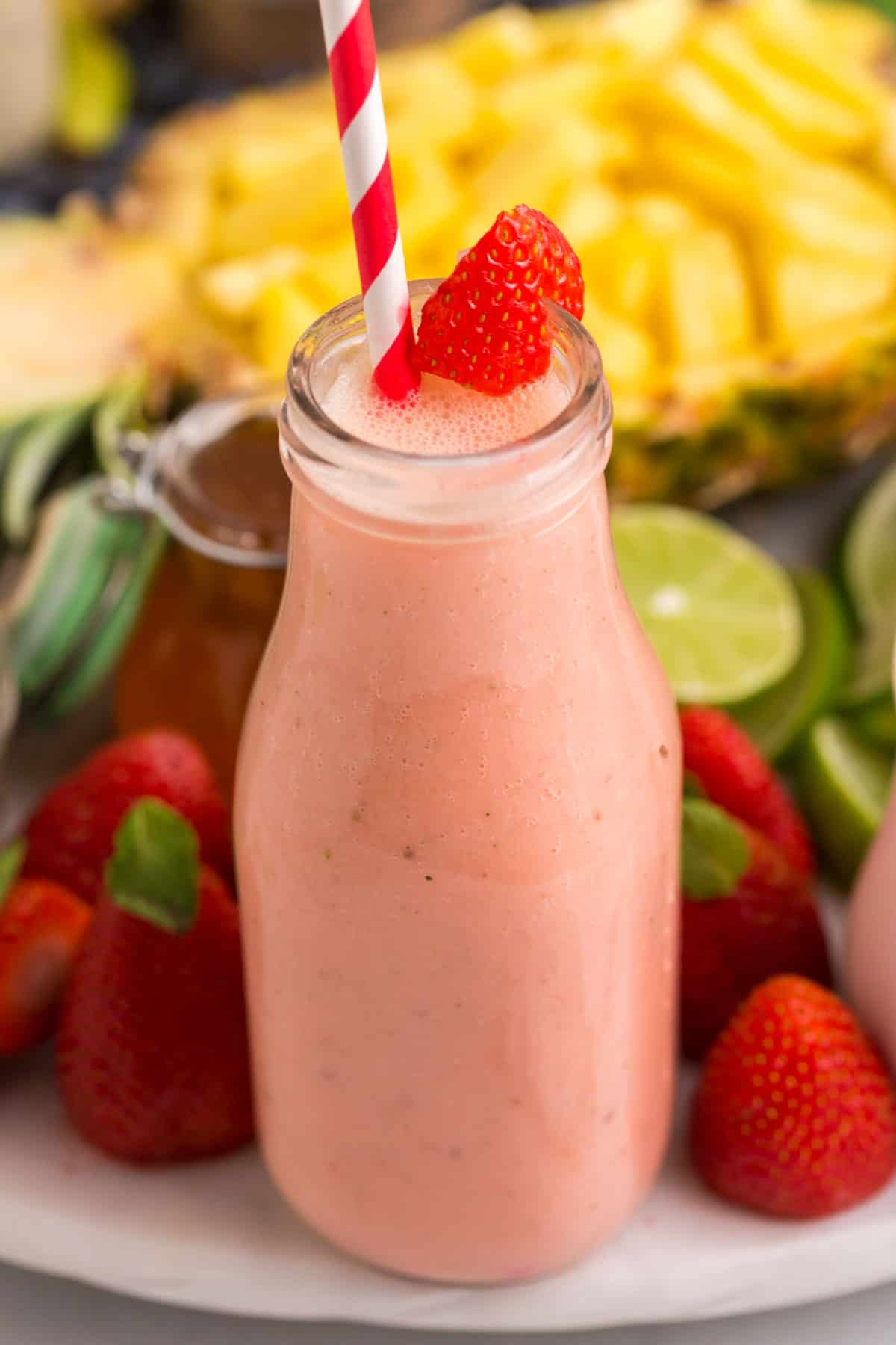Close up of strawberry smoothie with fresh fruit in the background.