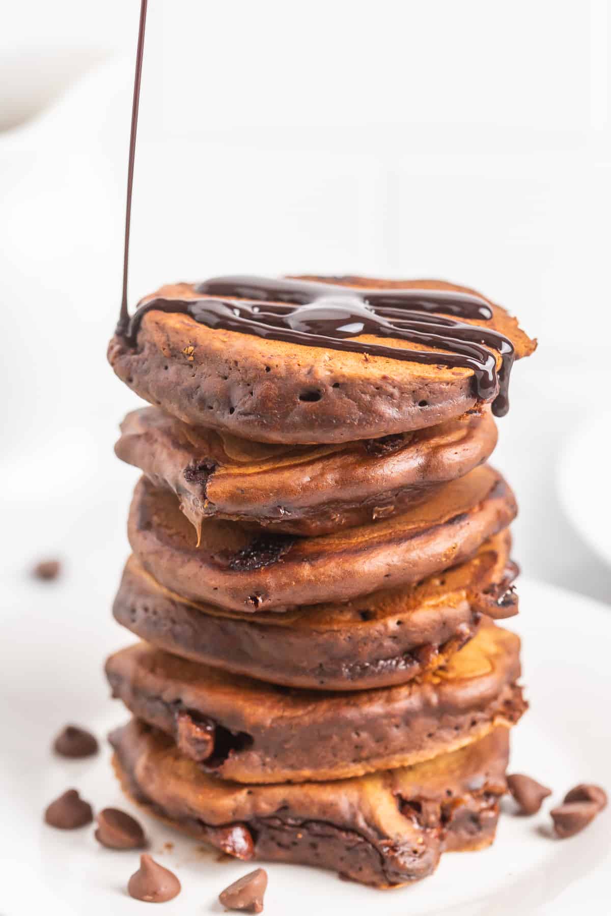 Syrup being poured on chocolate pancakes.