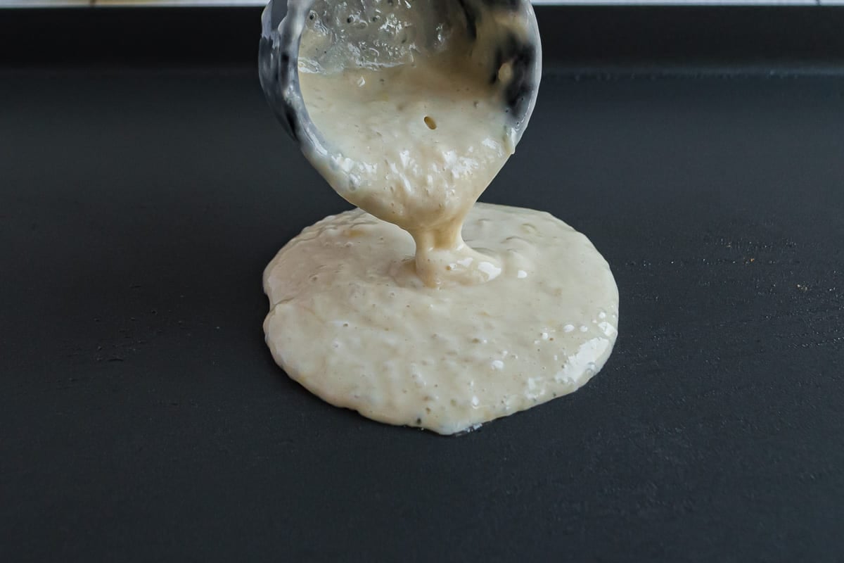 Pancake batter being poured onto a griddle.