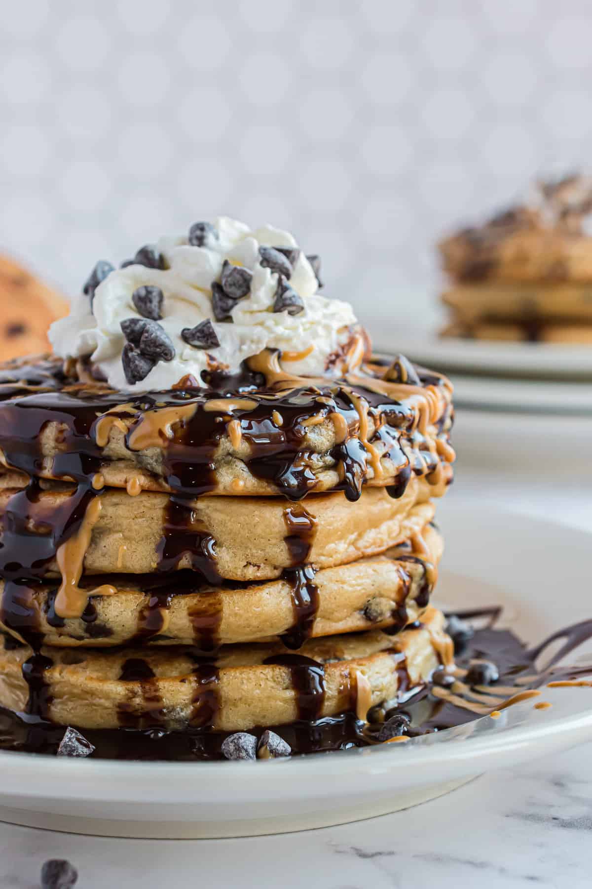 Stack of pancakes with chocolate syrup and whipped cream.