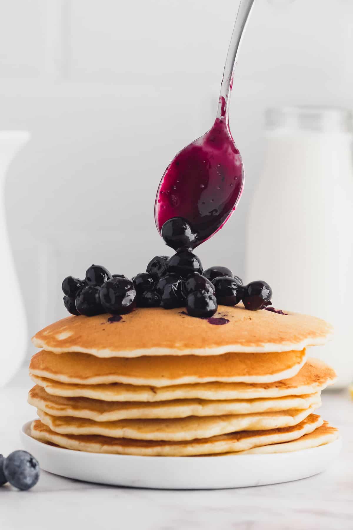 Blueberry sauce dripping down a stack of pancakes.