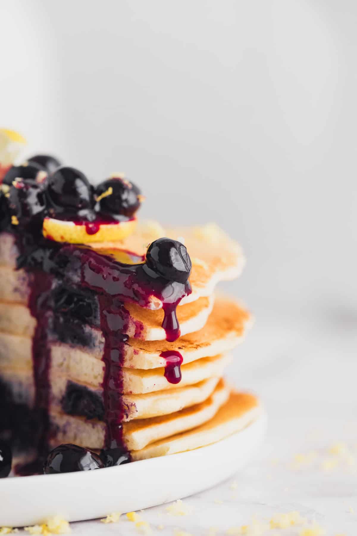 Blueberry sauce dripping down a stack of cut pancakes.