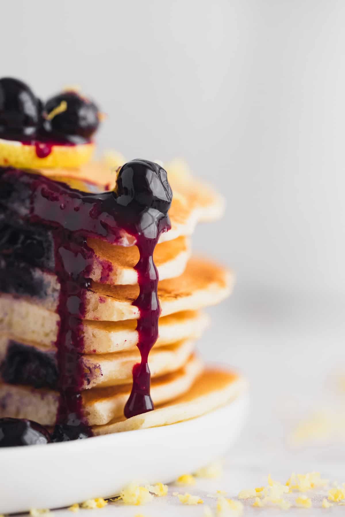 Blueberry sauce dripping down a stack of cut pancakes.