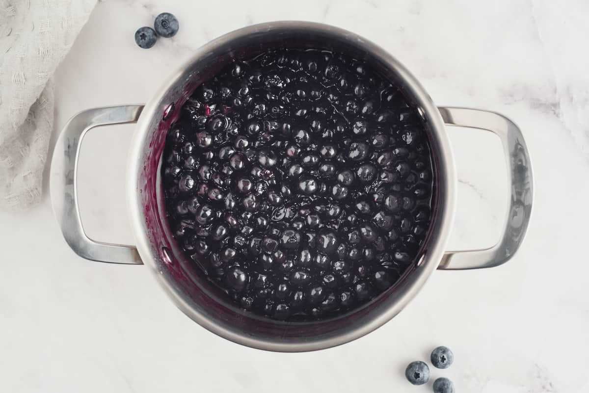 Cooked blueberry sauce in a metal saucepan.