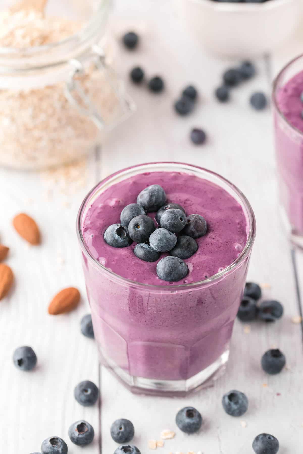 Blueberry smoothie in small glass, topped with fresh bluberries.