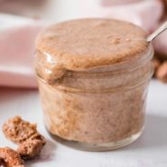 Almond butter overflowing out of a small jar.