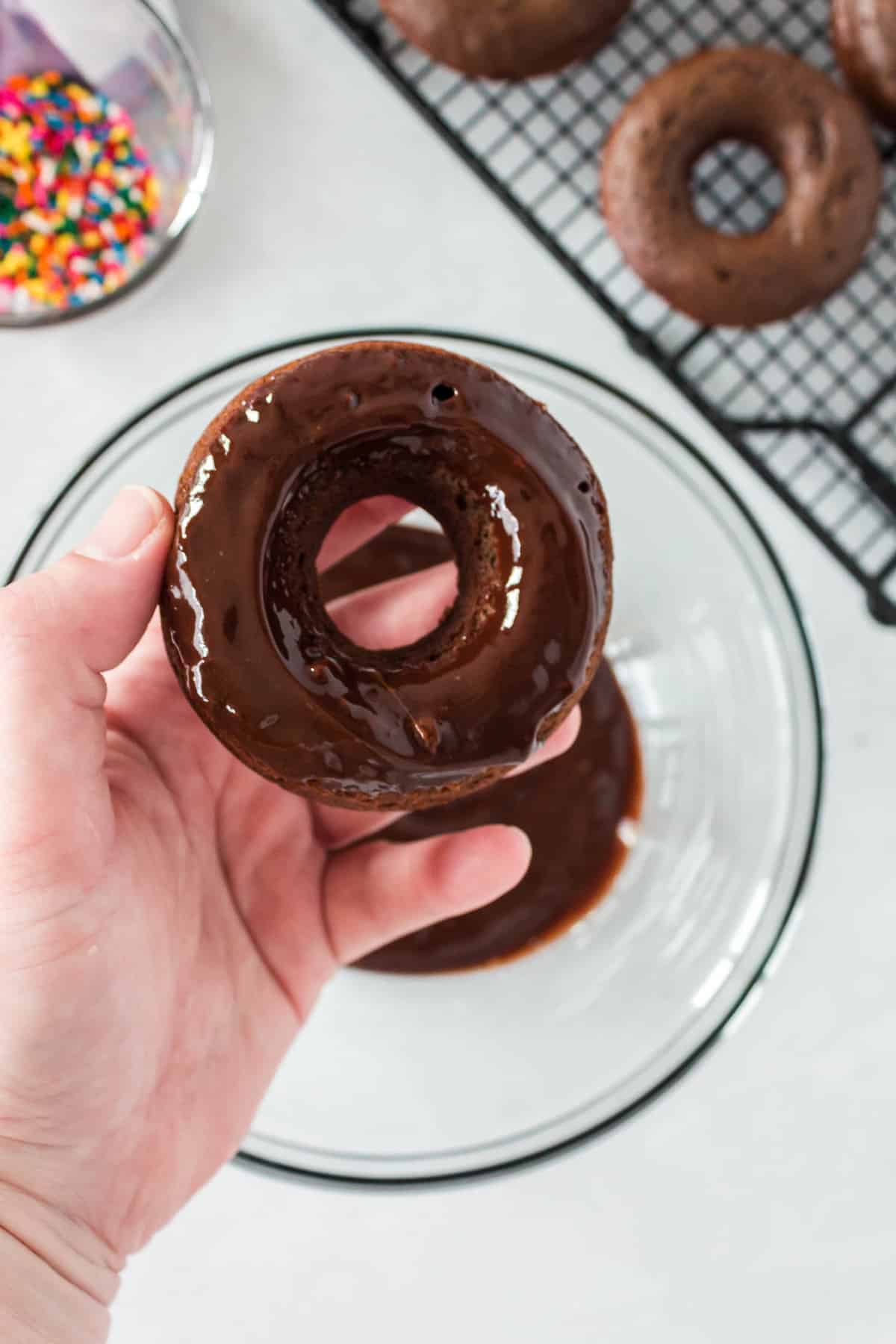 Donut with glaze in a hand.