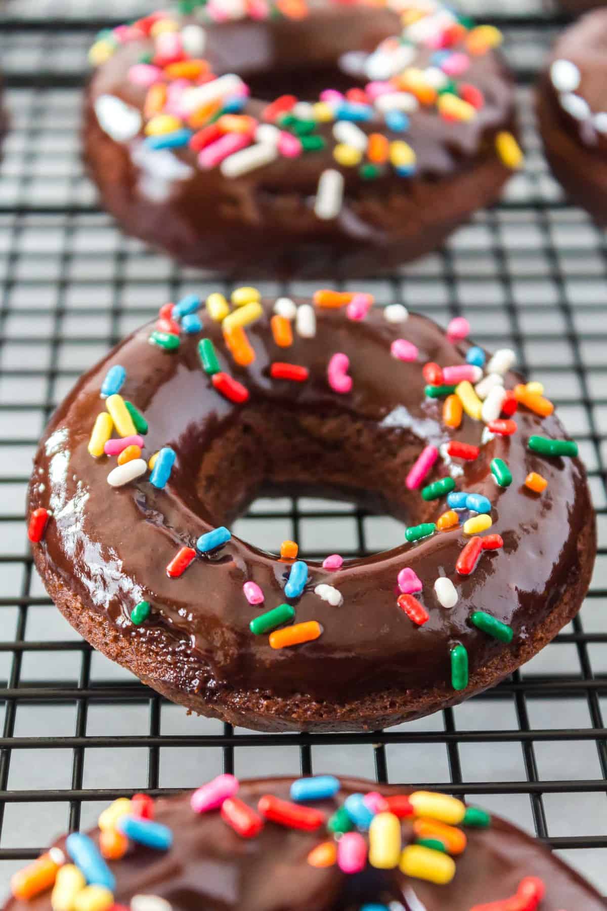 Chocolate donut with frosting on a cooling rack.