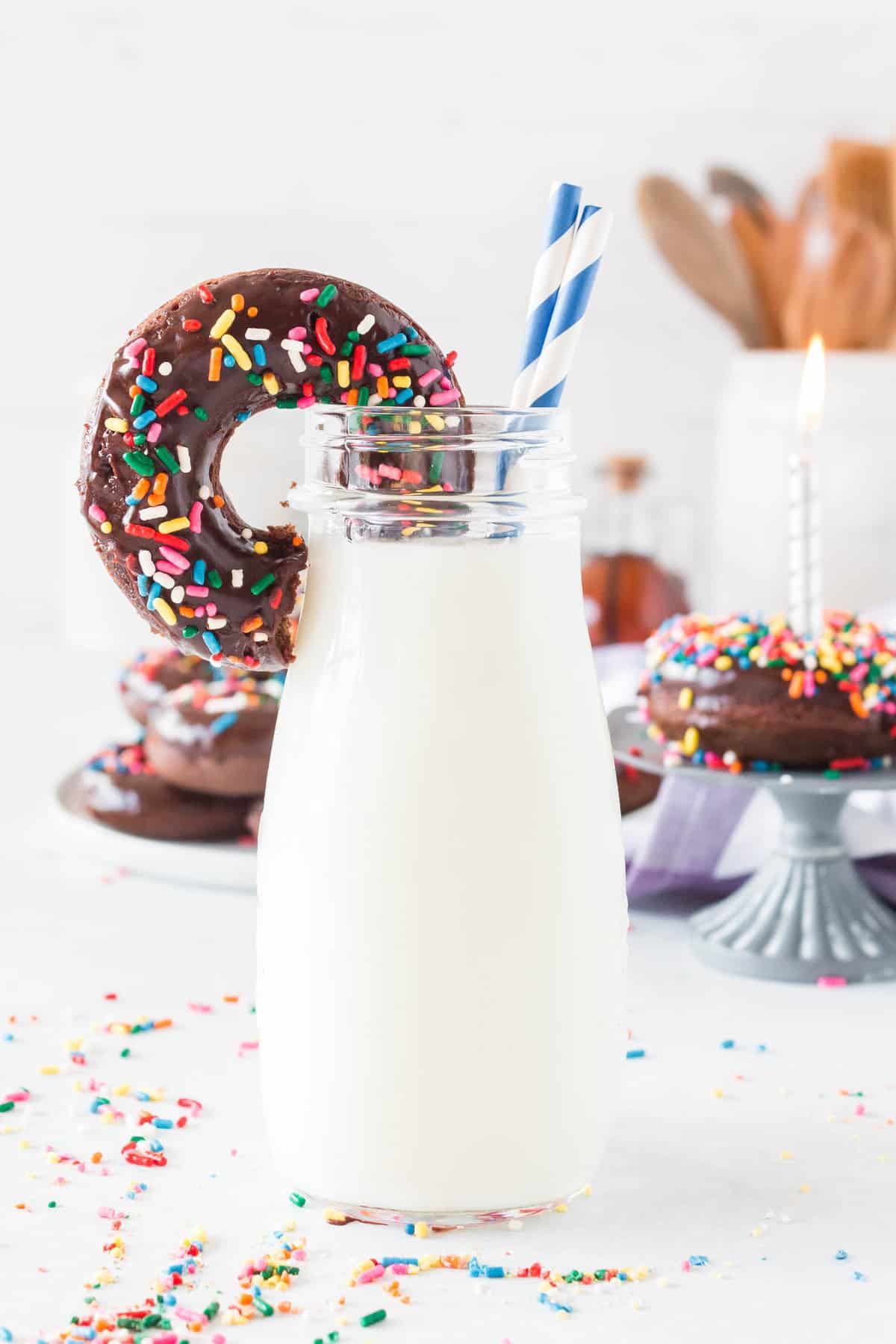 Donut propped on a bottle of milk.