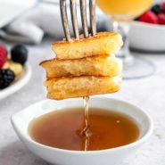 Pancakes on a fork, being dipped into syrup.
