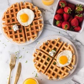 Overhead view of waffles topped with eggs, goat cheese, and chives.