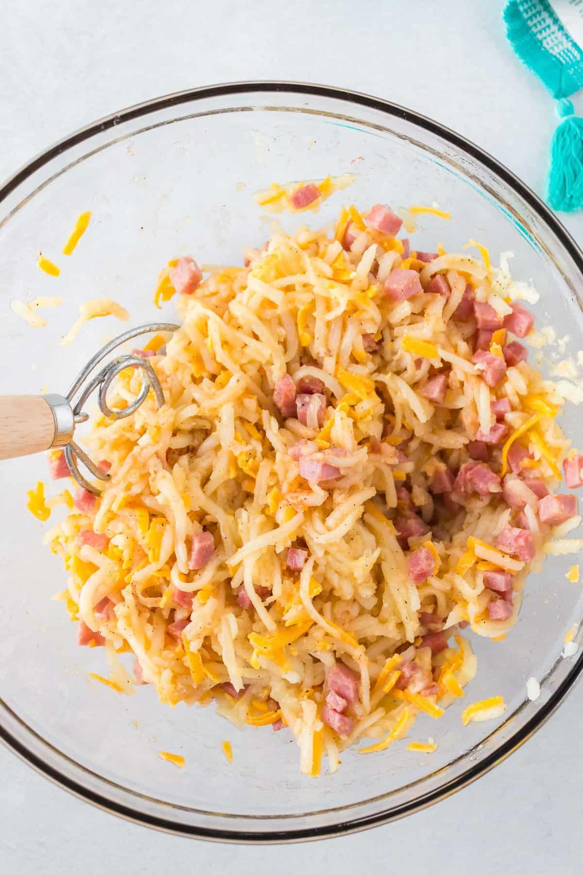 Uncooked hash browns mixed with ham and cheese.