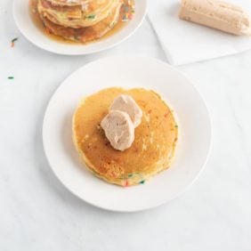 Compound butter made with cinnamon, atop a pancake on a white plate.