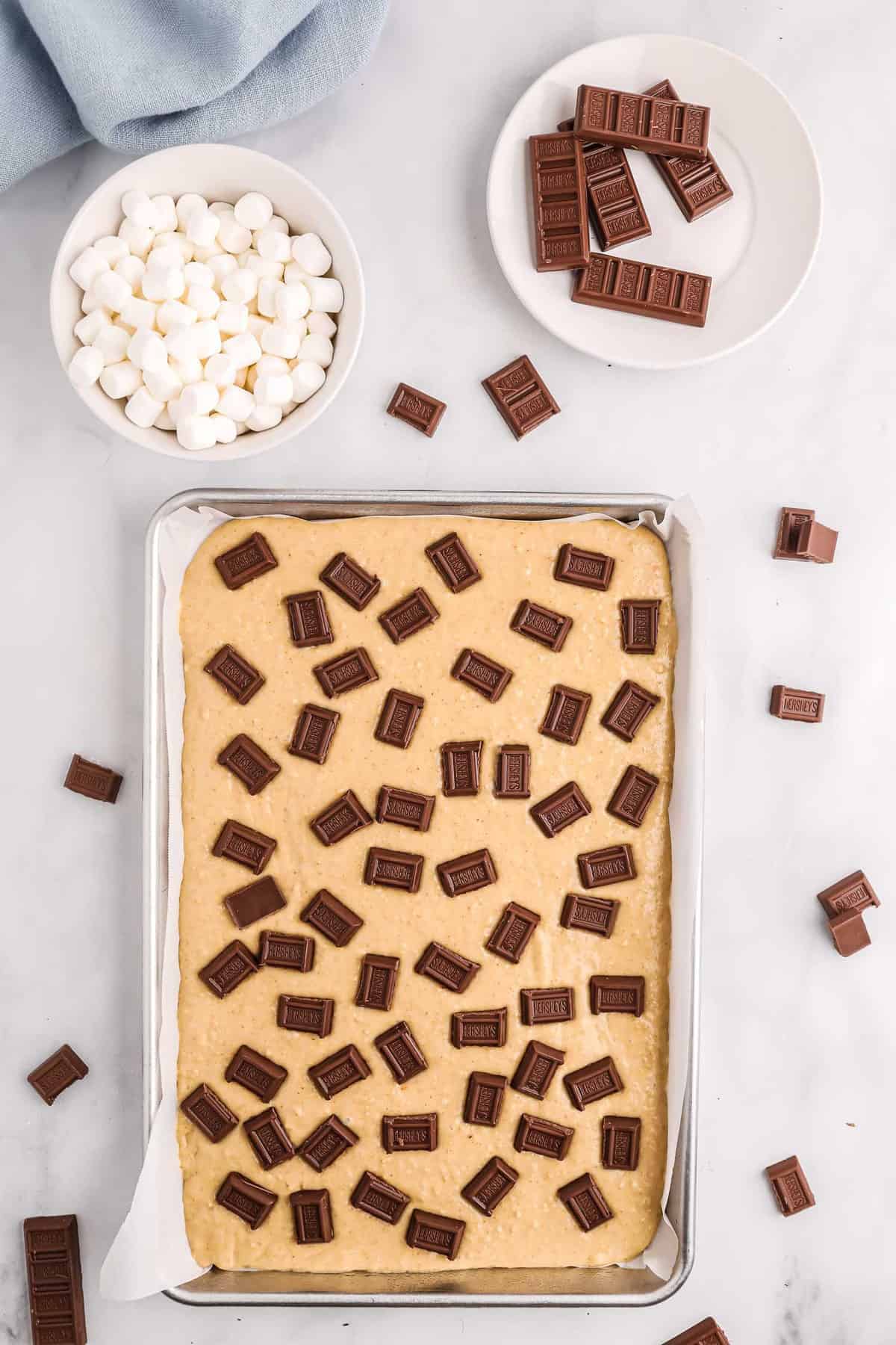 Unbaked sheet pan pancake topped with small candy bars.