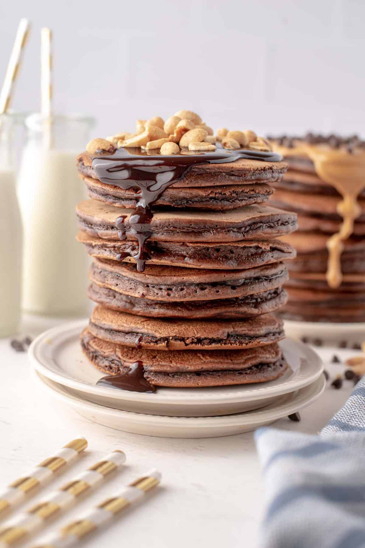 Very tall stack of chocolate pancakes with peanut butter.